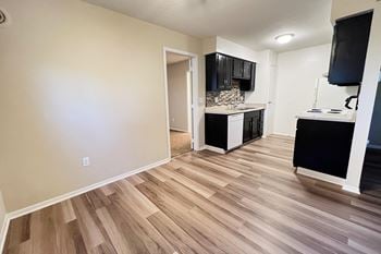 A living room and kitchen with wood flooring and black cabinets